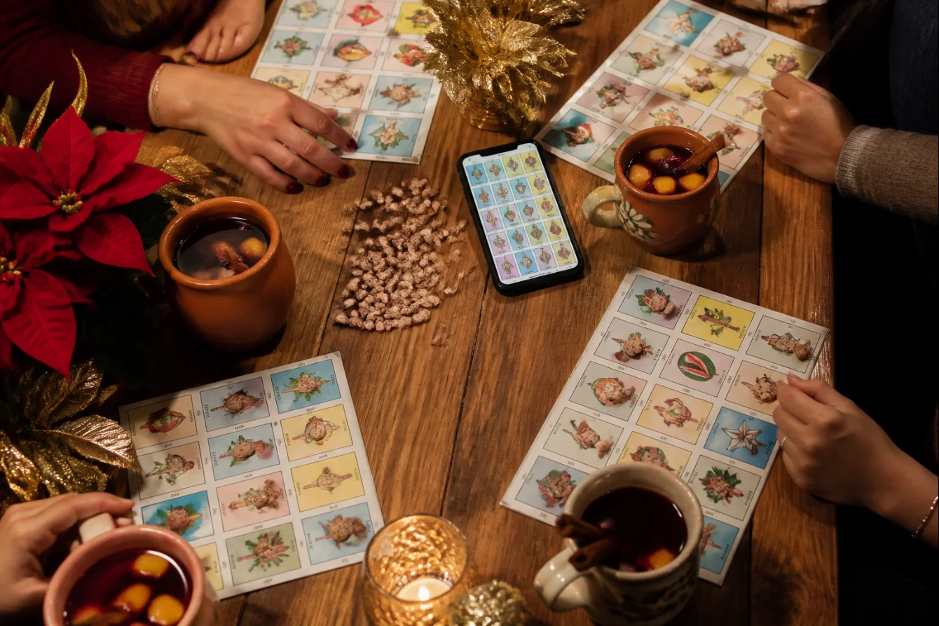 Mesa con tablas de lotería, frijoles, celular y ponche